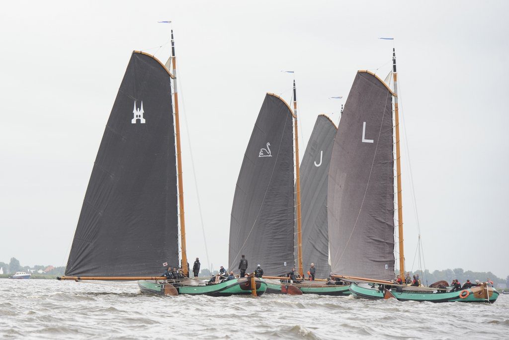 Voor de wind de drie groene skûtsjes van Sneek, Langweer en Lemmer bij elkaar