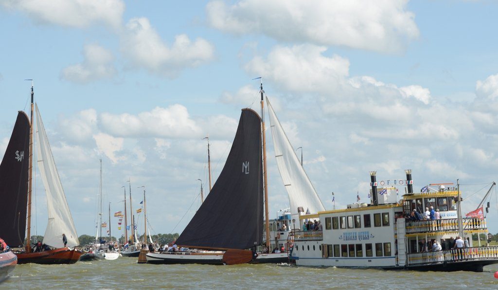 Het Huzumer skûtsje zeilt tussen de rondvaartboten door