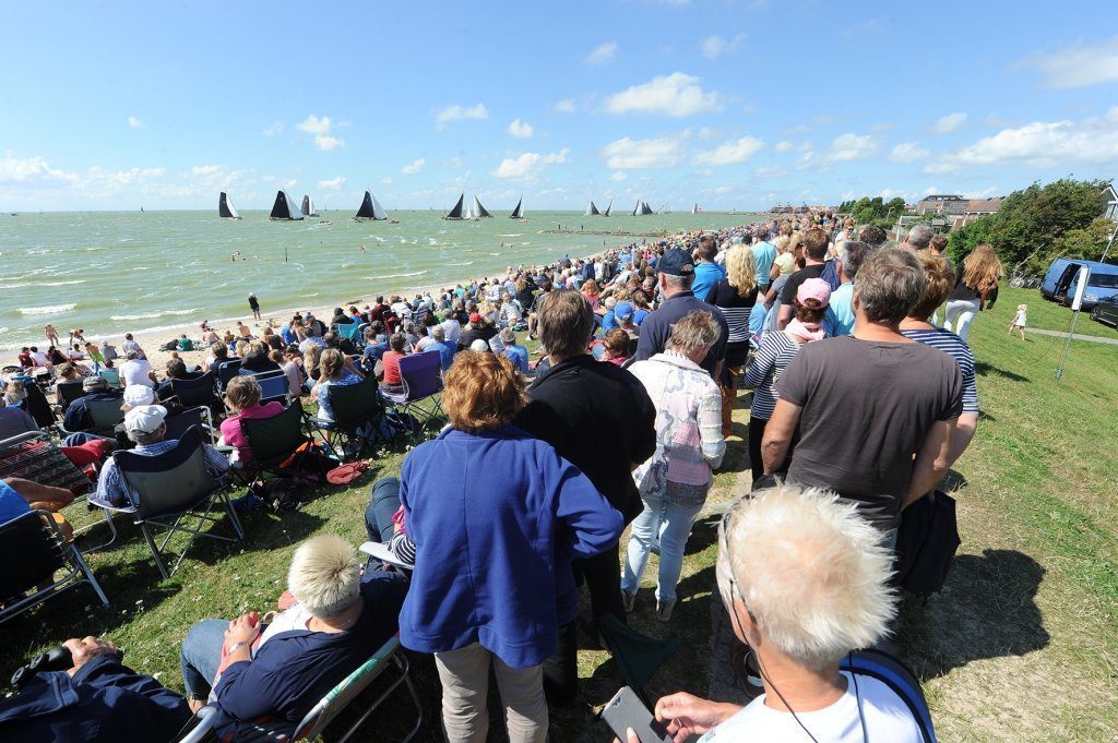 De vele toeschouwers op de IJsselmeerdijk volgen de skûtsjes